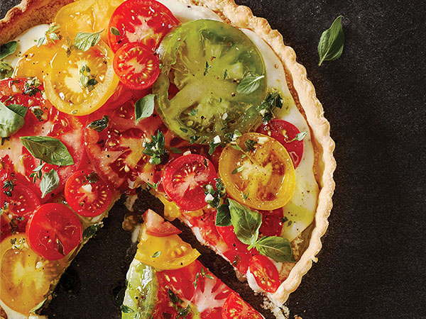 Tart topped with assorted colored tomatoes and topped with fresh herbs