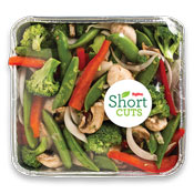 Broccoli, snow peas, white onions, mushrooms, and red bell peppers in a aluminum container and wrapped in plastic wrap