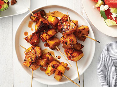 grilled pineapple on skewers on a plate